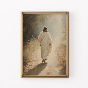 Puede incluir: Una pintura de una persona con una túnica blanca caminando por un sendero a través de un bosque, de espaldas al espectador. La persona camina hacia una luz brillante en la distancia. La pintura está enmarcada en un marco dorado.