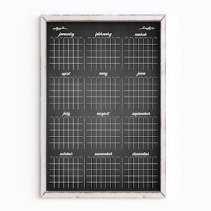 May include: A black chalkboard with a white frame, divided into twelve sections, one for each month of the year. Each section has a grid of squares for marking dates. The months are labeled in white text: January, February, March, April, May, June, July, August, September, October, November, December.