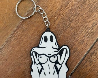 Peut inclure: Un porte-clés en forme de fantôme blanc et noir. Le fantôme a un design minimaliste avec un visage souriant et un corps stylisé. Le porte-clés comprend un porte-clés et une chaîne de couleur argentée.
