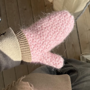 Peut inclure: Une moufle rose clair tricot&eacute;e &agrave; la main avec un motif textur&eacute;. La moufle est faite d'un fil doux et duveteux et poss&egrave;de un poignet c&ocirc;tel&eacute; de couleur neutre. Le pouce est s&eacute;par&eacute; des autres doigts. La moufle est con&ccedil;ue pour la chaleur et le confort.