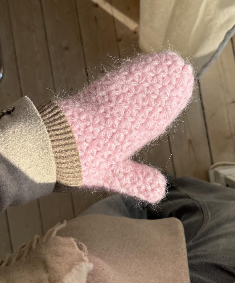 Peut inclure: Une moufle rose clair tricot&eacute;e &agrave; la main avec un motif textur&eacute;. La moufle est faite d'un fil doux et duveteux et poss&egrave;de un poignet c&ocirc;tel&eacute; de couleur neutre. Le pouce est s&eacute;par&eacute; des autres doigts. La moufle est con&ccedil;ue pour la chaleur et le confort.
