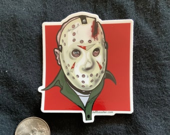 May include: A sticker featuring a stylized illustration of Jason Voorhees' hockey mask with blood splatter, set against a red background. The sticker has a white border and the website JeffLassiter.com is visible.