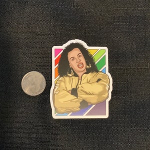May include: A sticker featuring a cartoon illustration of a woman with dark hair and a gold jacket. She is wearing large hoop earrings and has a colorful rainbow background behind her.