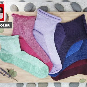 Peut inclure: Une collection de chaussettes colorées en teintes de turquoise, rose, violet, bleu et bordeaux, disposées sur une surface en bois. Les chaussettes sont étiquetées avec le texte "011S COLOR" et "MEDICAL EFFECT".