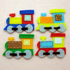 Peut inclure: Quatre trains en feutre jouet de différentes couleurs, chacun avec trois roues et une fenêtre rectangulaire. Les trains sont rouge, jaune, vert et bleu.