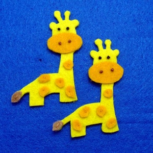May include: Two yellow felt giraffe cutouts with orange spots and brown accents. The giraffes have orange faces and brown eyes. The background is a solid blue.