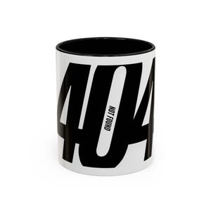 May include: A white ceramic mug with a black interior and rim. The exterior features large, bold black numbers reading 404, with the words NOT FOUND printed vertically in a smaller black sans-serif font within the centre zero digit.