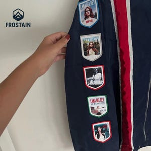 Puede incluir: Chaqueta azul marino con rayas rojas y blancas y m&uacute;ltiples parches de Lana Del Rey. Los parches incluyen im&aacute;genes de la cantante e informaci&oacute;n de la gira. La chaqueta tiene cierre de cremallera y un logotipo de Frostain.
