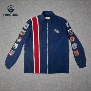 Puede incluir: Chaqueta azul marino con cremallera y una franja roja y blanca en la parte delantera. La chaqueta tiene parches en las mangas y el texto "IDM" en el pecho. El logotipo "FROSTAIN" est&aacute; en la esquina superior izquierda.