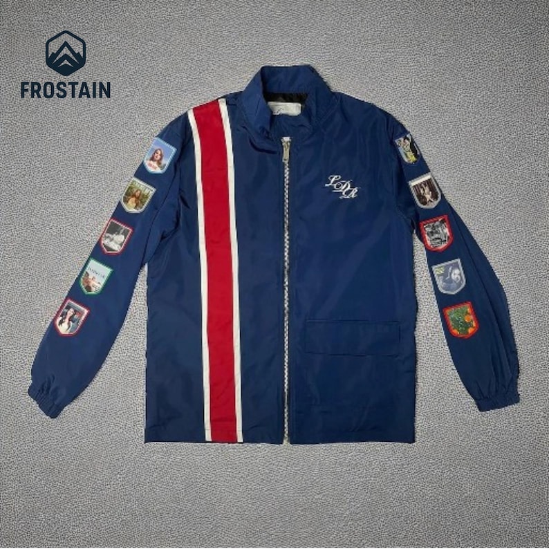 Puede incluir: Chaqueta azul marino con cremallera y una franja roja y blanca en la parte delantera. La chaqueta tiene parches en las mangas y el texto "IDM" en el pecho. El logotipo "FROSTAIN" est&aacute; en la esquina superior izquierda.