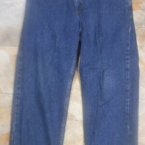 May include: A pair of blue denim jeans with a straight leg fit. The jeans have a classic five-pocket style and a button fly.