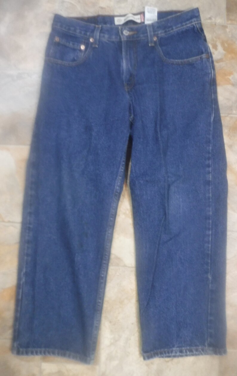 May include: A pair of blue denim jeans with a straight leg fit. The jeans have a classic five-pocket style and a button fly.