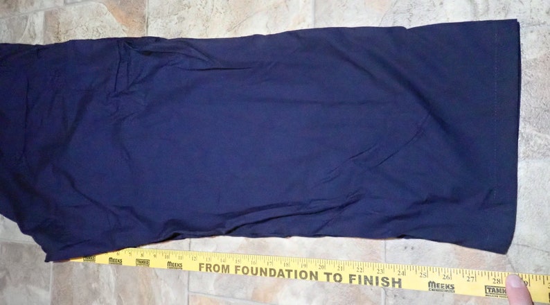 May include: A dark blue pair of pants with a yellow measuring tape at the bottom. The tape reads "From Foundation to Finish".