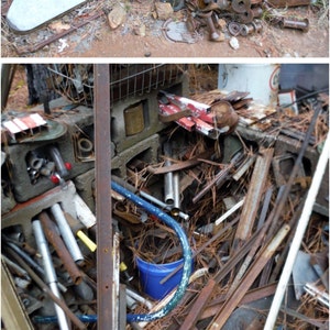 May include: A pile of scrap metal and rusty metal objects, including pipes, rods, and metal sheets, are piled on top of concrete blocks. A blue bucket is visible in the lower right corner of the image.