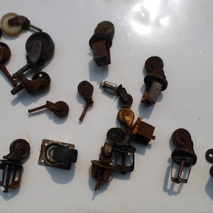 Puede incluir: Una colección de ruedas antiguas de varios diseños y tamaños. Las ruedas son principalmente de metal y presentan un aspecto oxidado y envejecido. Algunas tienen ruedas, otras placas de montaje.