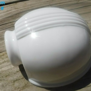May include: White glass light fixture with a rounded shape and three horizontal ridges. The fixture has a side opening for mounting.