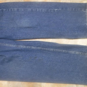 May include: A pair of blue denim jeans with a straight leg fit. The jeans have a classic five-pocket style and a dark wash.