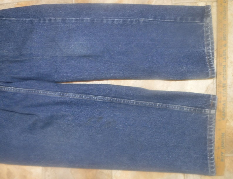 May include: A pair of blue denim jeans with a straight leg fit. The jeans have a classic five-pocket style and a dark wash.