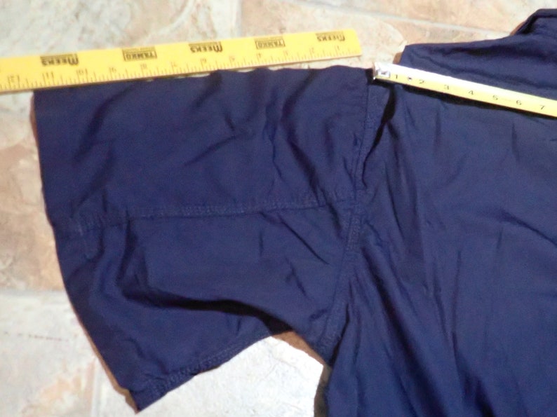 May include: A navy blue short-sleeved shirt with a seam down the center of the sleeve.