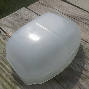 Op de afbeelding: Een wit, koepelvormig object van plastic met een glad, glanzend oppervlak. Het object ligt op een houten oppervlak.