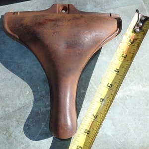 May include: A rusty cast iron foot for a piece of furniture. The foot is shaped like a bell and has a hole in the top for mounting. The foot is 8 inches long.