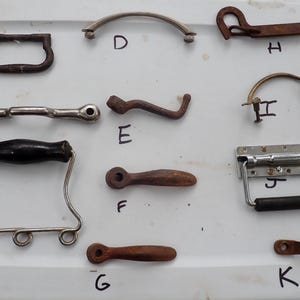 Könnte beinhalten: Sortiment von 11 Vintage-Metallgriffen in verschiedenen Stilen und Ausführungen, darunter Silber, Chrom und Schwarz. Einige Griffe haben einen Gummigriff. Die Griffe sind von A bis K beschriftet.