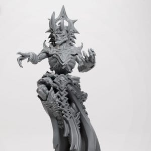 Op de afbeelding: Een grijze, gedetailleerde figuur van een skeletfiguur met een kroon en sierlijke bepantsering. De figuur heeft uitgestrekte armen en een vloeiende cape, met ingewikkelde ontwerpelementen. De algehele esthetiek suggereert een fantasie- of gotisch thema.