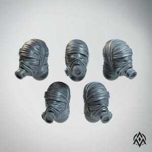 May include: Five gray, stylized gas mask heads with wrapped fabric details. Each mask features a circular respirator and is designed with a post-apocalyptic or sci-fi aesthetic. The masks are arranged against a neutral background.