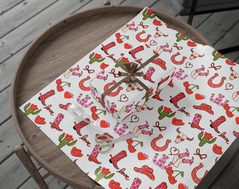 May include: White wrapping paper with a repeating pattern of red cowboy boots, horseshoes, cacti, cherries, and hearts. The text "love" is repeated throughout the pattern.