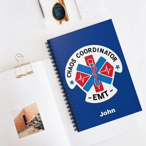 Może przedstawiać: Niebieski notes w spirali z białym symbolem gwiazdy życia i tekstem "Chaos Coordinator - EMT - John".