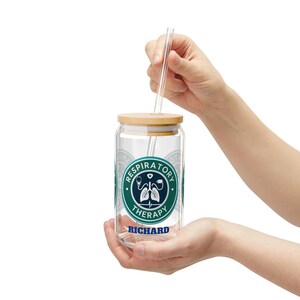May include: A clear glass can-shaped tumbler with a wooden lid and a clear straw. The tumbler features a Respiratory Therapy logo in teal and white, with the name "RICHARD" in blue. The tumbler is held by two hands.