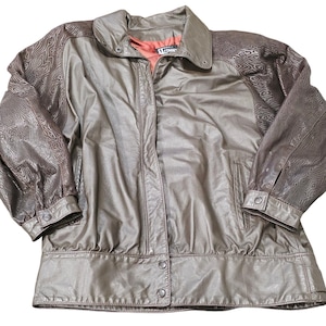 May include: A vintage brown jacket with a button-up front, a collar, and a red interior lining. The sleeves have a patterned design, and the jacket has two front pockets. The jacket is made of a shiny material.