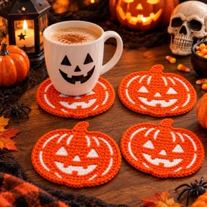 Peut inclure: Un mug en céramique blanche avec un visage de citrouille d'Halloween noir contenant une boisson chaude, accompagné de trois dessous de verre ronds en crochet orange et blanc représentant des citrouilles sur une surface en bois.