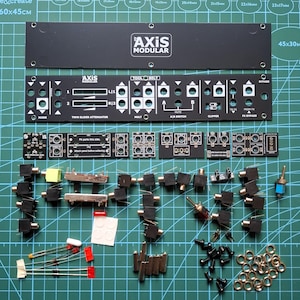 May include: A modular synthesiser DIY kit featuring two black metal faceplates with white text including Axis Modular and Tool Belt. The kit includes multiple small circuit boards, various black audio jacks, two toggle switches, metal washers, screws, and electronic components like diodes and LEDs.