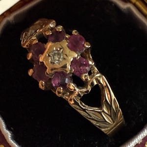 May include: A gold ring with a cluster of pink gemstones and a single diamond in the center. The ring is set in a floral design.