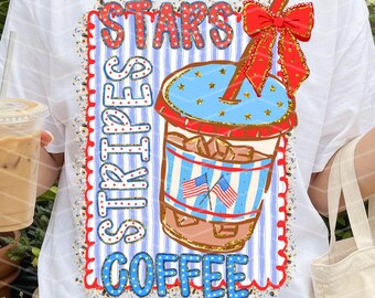 May include: White t-shirt with a graphic of a coffee cup with the text "STARS STRIPES COFFEE". The coffee cup design features red, white, and blue colors with a red bow. The person is holding a coffee drink and a small tote bag.