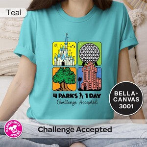 Puede incluir: Camiseta de color turquesa con un gr&aacute;fico colorido que presenta cuatro iconos de parques tem&aacute;ticos: un castillo, una esfera geod&eacute;sica, un &aacute;rbol y una torre. El texto dice "4 Parks 1 Day Challenge Accepted". La camiseta es una Bella+Canvas 3001.