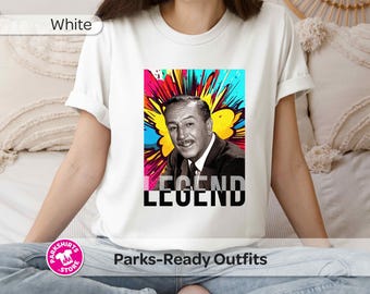 May include: A white short-sleeved t-shirt featuring a graphic print of a black and white portrait of Walt Disney set against a vibrant, multi-colored abstract explosion background, with the word LEGEND printed in bold black letters below.
