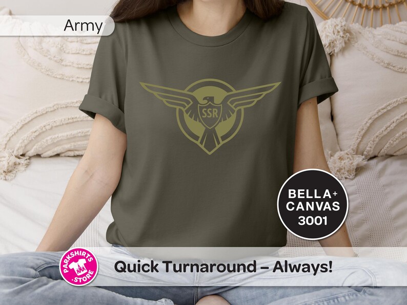 May include: Olive green t-shirt with a gold emblem of wings and the letters "SSR". The shirt is a Bella+Canvas 3001. The text "Quick Turnaround - Always!" is also visible.