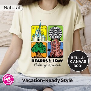 Puede incluir: Camiseta color crema con un gr&aacute;fico colorido que presenta cuatro cuadrados con im&aacute;genes ic&oacute;nicas de parques tem&aacute;ticos. El texto "4 PARKS 1 DAY Challenge Accepted" est&aacute; debajo de los cuadrados. La camiseta tambi&eacute;n tiene el texto "BELLA+ CANVAS 3001".