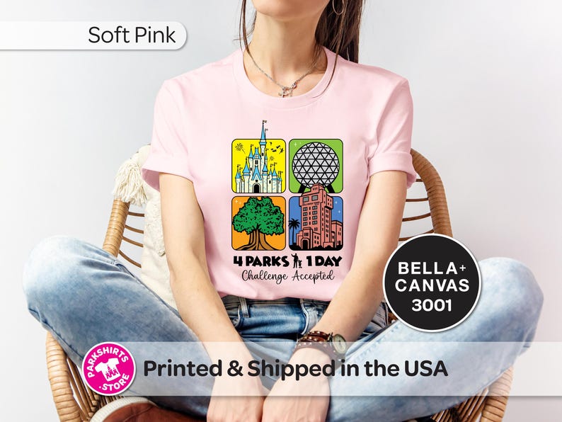Puede incluir: Camiseta rosa claro con un gr&aacute;fico colorido que presenta cuatro iconos de parques tem&aacute;ticos. El dise&ntilde;o incluye un castillo, una esfera geod&eacute;sica, un &aacute;rbol y un edificio alto. El texto dice "4 Parks 1 Day Challenge Accepted."