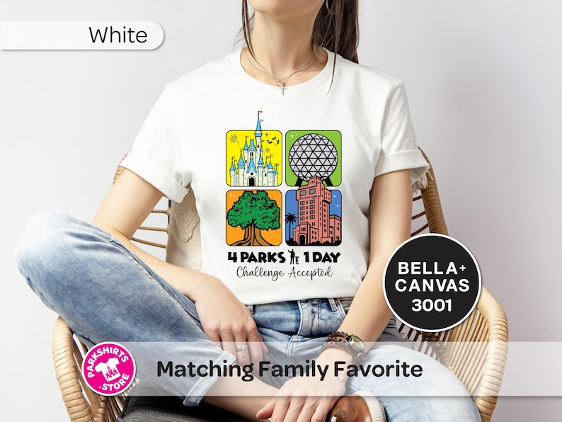 Puede incluir: Camiseta blanca con un gr&aacute;fico colorido que presenta cuatro iconos de parques tem&aacute;ticos. El dise&ntilde;o incluye un castillo, una esfera geod&eacute;sica, un &aacute;rbol y una torre, con el texto "4 PARKS 1 DAY Challenge Accepted". La camiseta est&aacute; etiquetada como "BELLA+ CANVAS 3001".