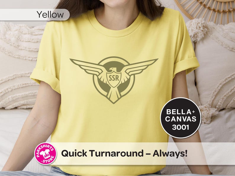 May include: Pale yellow t-shirt with a circular emblem featuring a stylized eagle and the letters "SSR". The shirt also has the text "Quick Turnaround - Always!" and the brand name "Bella + Canvas 3001".