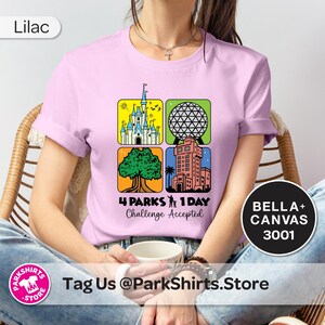 Puede incluir: Camiseta lila con un gr&aacute;fico colorido que presenta cuatro iconos de parques tem&aacute;ticos y el texto "4 Parks 1 Day Challenge Accepted". La camiseta es de material Bella+Canvas 3001.