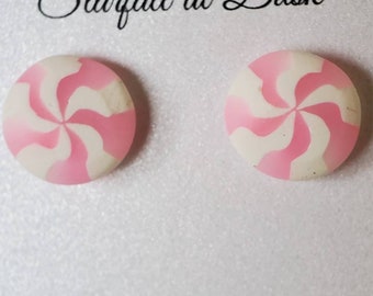 May include: A pair of round stud earrings with a pink and white swirl design. The earrings are displayed on a white card with the text "Starfall at Dusk" and a logo of a donut. The text "Nickel free jewelry" is also visible.