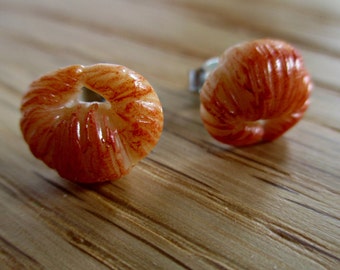May include: A pair of stud earrings featuring a rounded, textured shape with a translucent white base and reddish-orange streaks. The surface has a ribbed, organic appearance with a small central opening, and each earring includes a metal post backing.