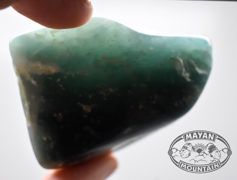 May include: A smooth, green, and black gemstone with a slightly irregular shape.