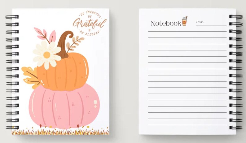 May include: Spiral-bound notebook with a fall theme. The cover features a stacked orange and pink pumpkin design with floral accents and the words "Be Thankful, Be Grateful, Be Blessed." The interior pages are lined.