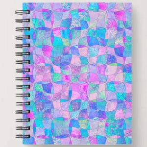 May include: Spiral-bound notebook with a colorful abstract design. The cover features a repeating pattern of overlapping shapes in shades of pink, blue, and purple. The notebook has a silver spiral binding.