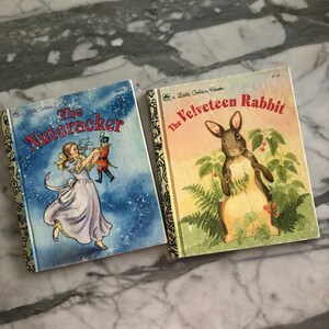 Puede incluir: Dos libros vintage de Little Golden Books. El Cascanueces presenta a una niña con un vestido blanco bailando con un soldado cascanueces. El Conejo de Peluche presenta a un conejo marrón en un entorno de bosque verde. Ambos libros tienen una columna vertebral dorada y una cubierta azul.